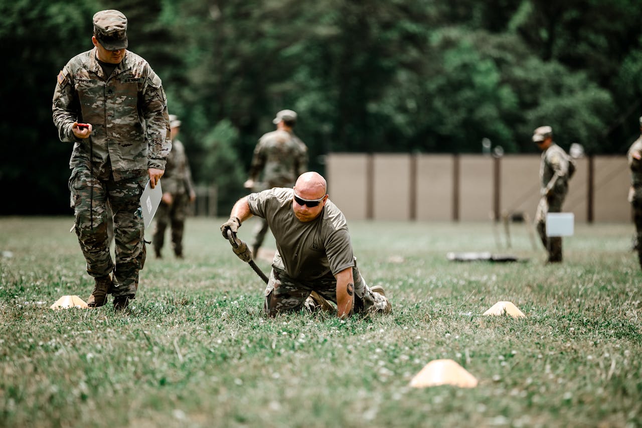 A group of soldiers engaged in a rigorous outdoor military training session in a grassy field.